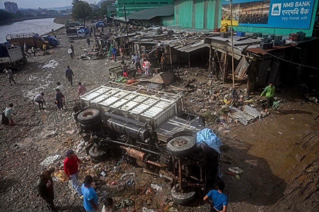 Caminhão tombado e casas danificadas após a inundação no Nepal.