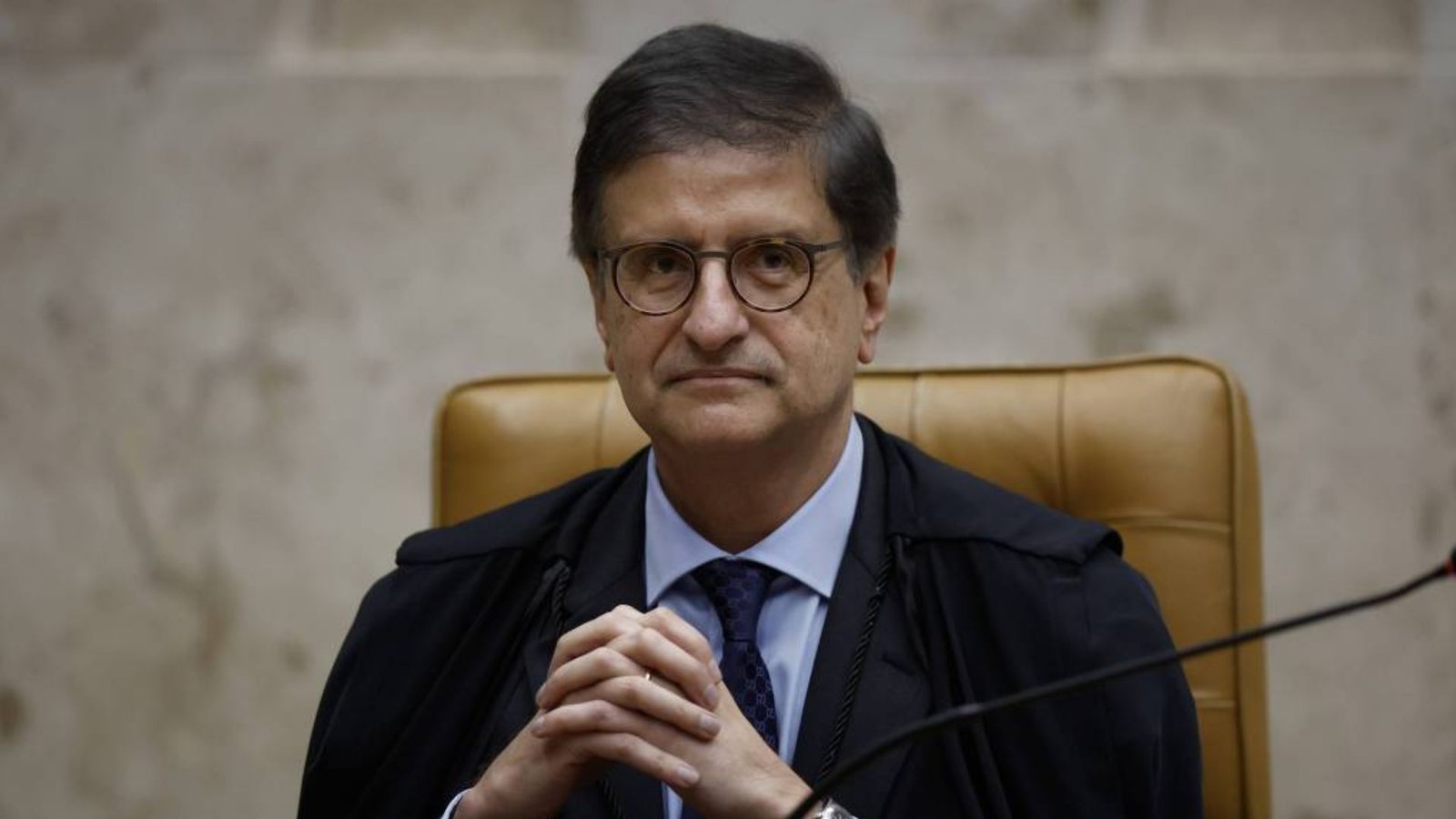 Paulo Gonet, de toga, sentado diante de um microfone.