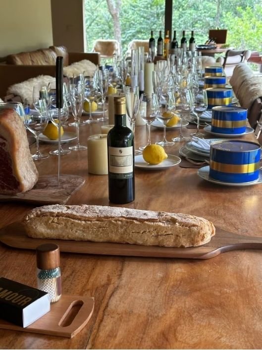 Mesa preparada com taças, vinhos, pães e latas de caviar.