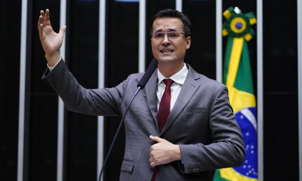 Deltan Dallagnol fala ao microfone com a mão levantada