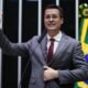Deltan Dallagnol fala ao microfone com a mão levantada