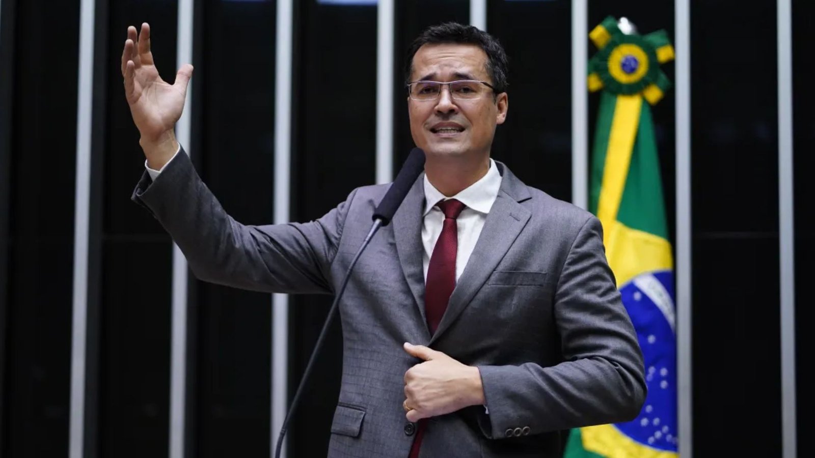 Deltan Dallagnol fala ao microfone com a mão levantada