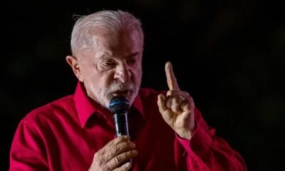 Lula fala ao microfone com o dedo erguido