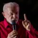 Lula fala ao microfone com o dedo erguido