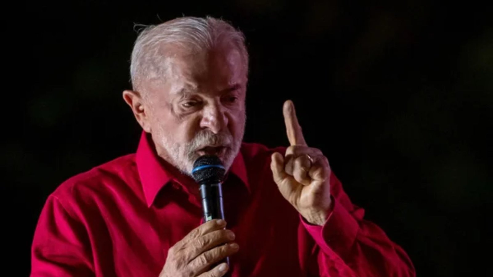 Lula fala ao microfone com o dedo erguido