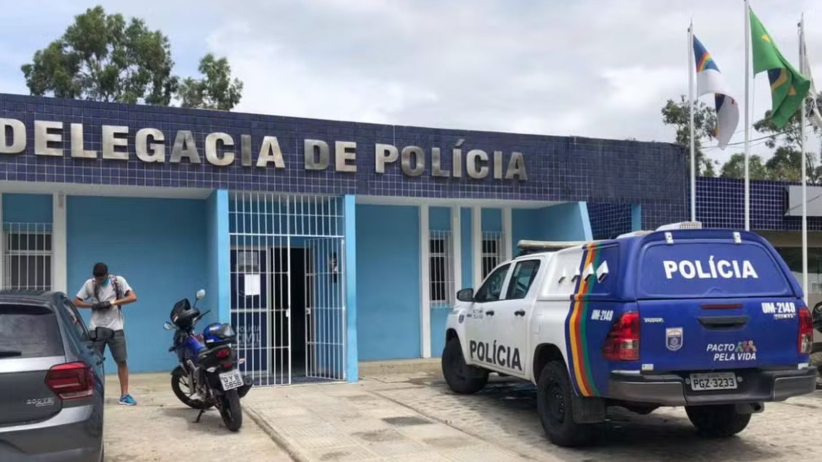 Delegacia de Polícia com viaturas estacionadas em frente ao prédio.