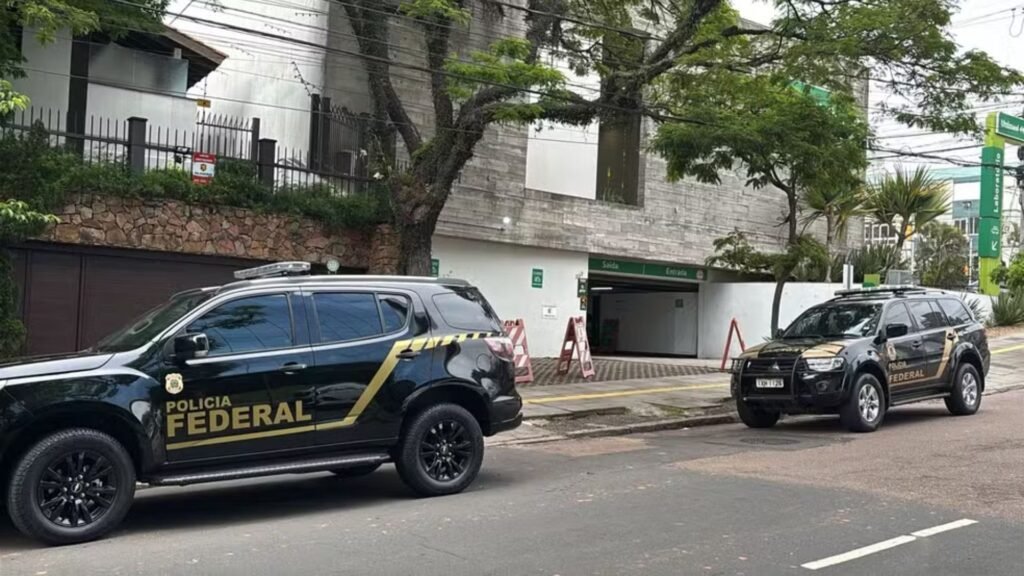 Duas viaturas da Polícia Federal estacionadas em frente a um prédio