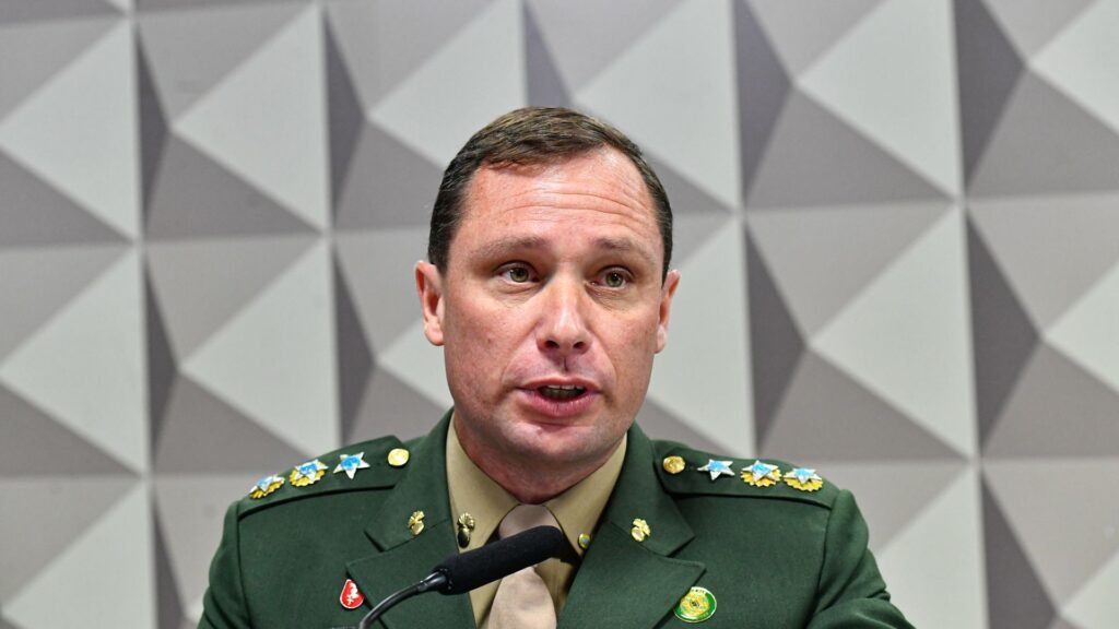 Mauro Cid de uniforme militar diante de um microfone.