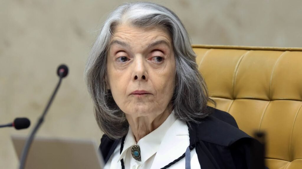 Cármen Lúcia de toga, sentada diante de microfones.