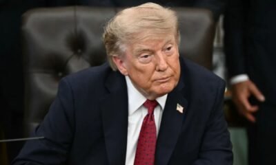 Donald Trump sentado, com terno azul-marinho e gravata vermelha.