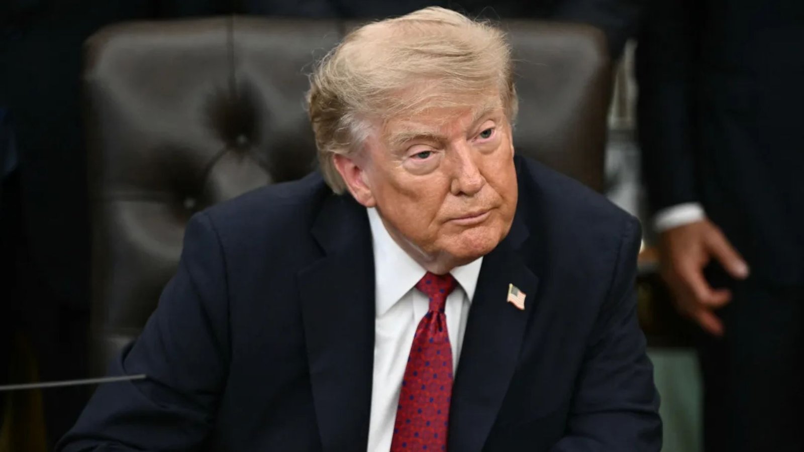 Donald Trump sentado, com terno azul-marinho e gravata vermelha.